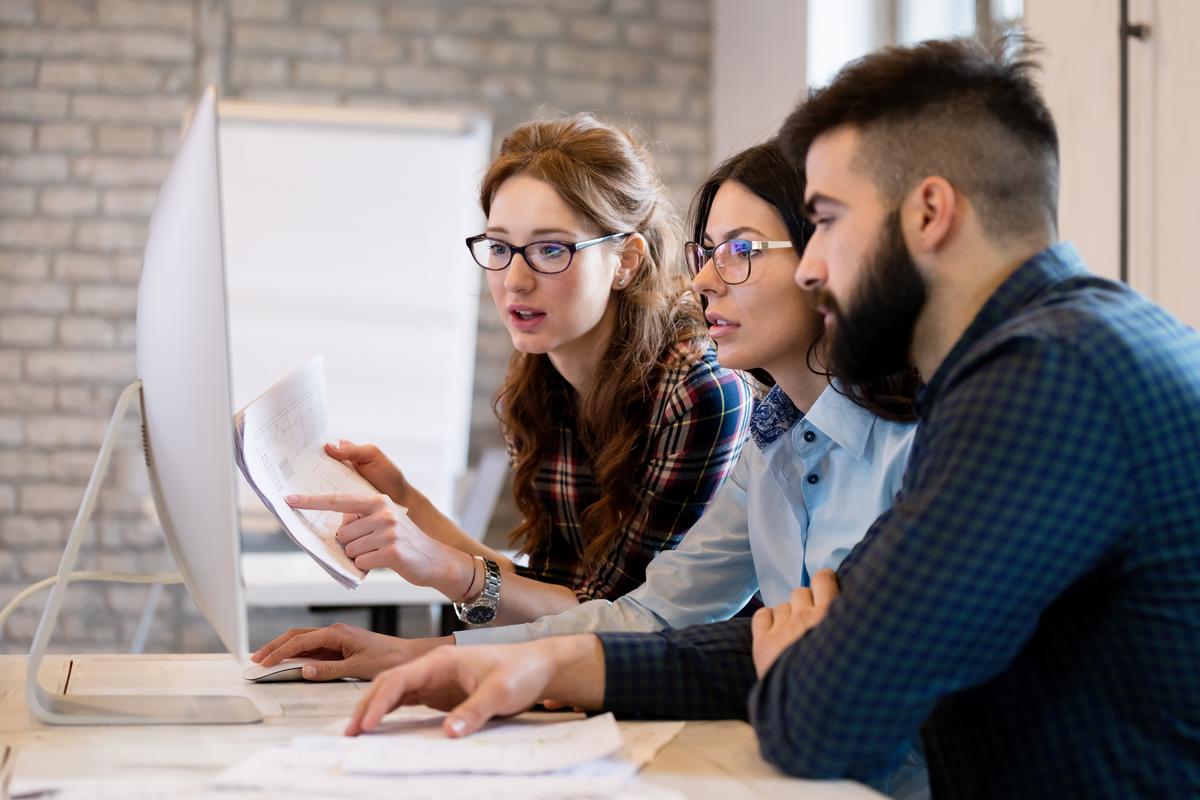 Three young business people looking at computer
