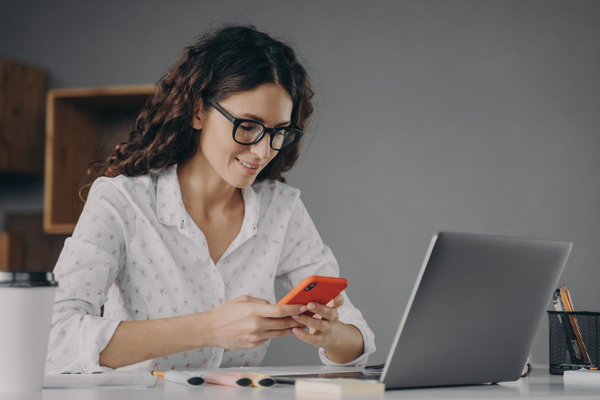 Woman working on laptop and using mobile phone