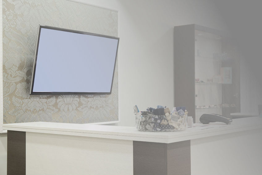 TV showing a white screen, hanging behind a reception counter